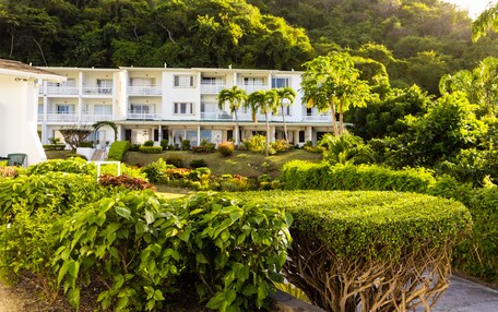 A multi-story hotel with balconies, surrounded by lush greenery and well-maintained gardens.