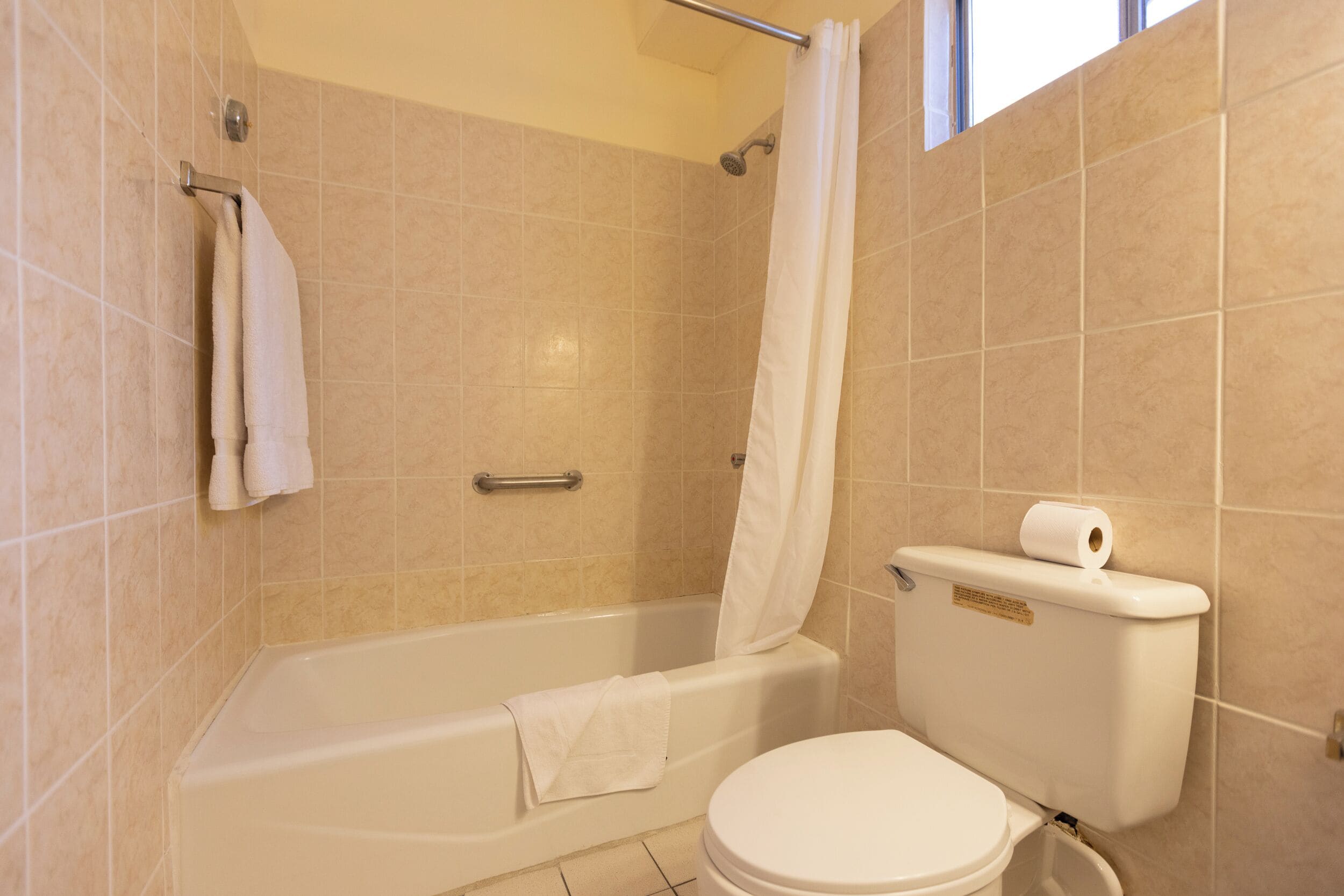 Un baño con bañera, inodoro y cortina de ducha.