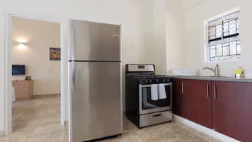 A kitchen with a stainless steel refrigerator, a stove, and a sink.