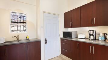 A kitchen with a white door, stainless steel sink, and wooden cabinets.