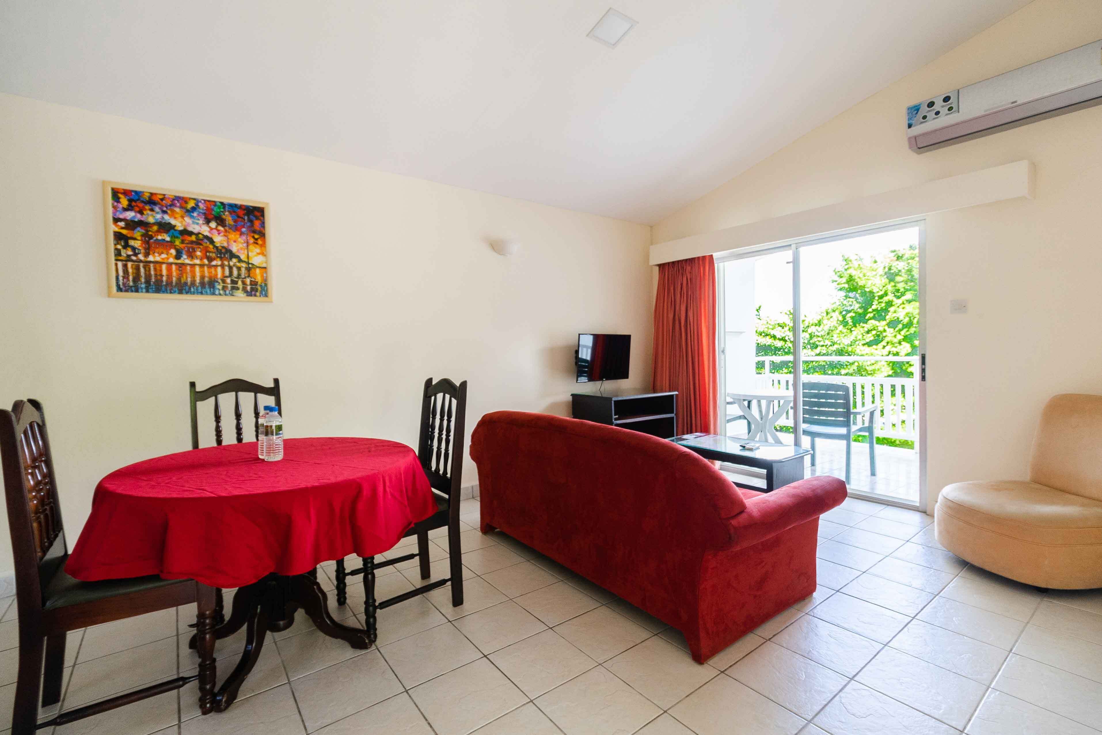 A living room with a dining table, red sofa, and a TV.