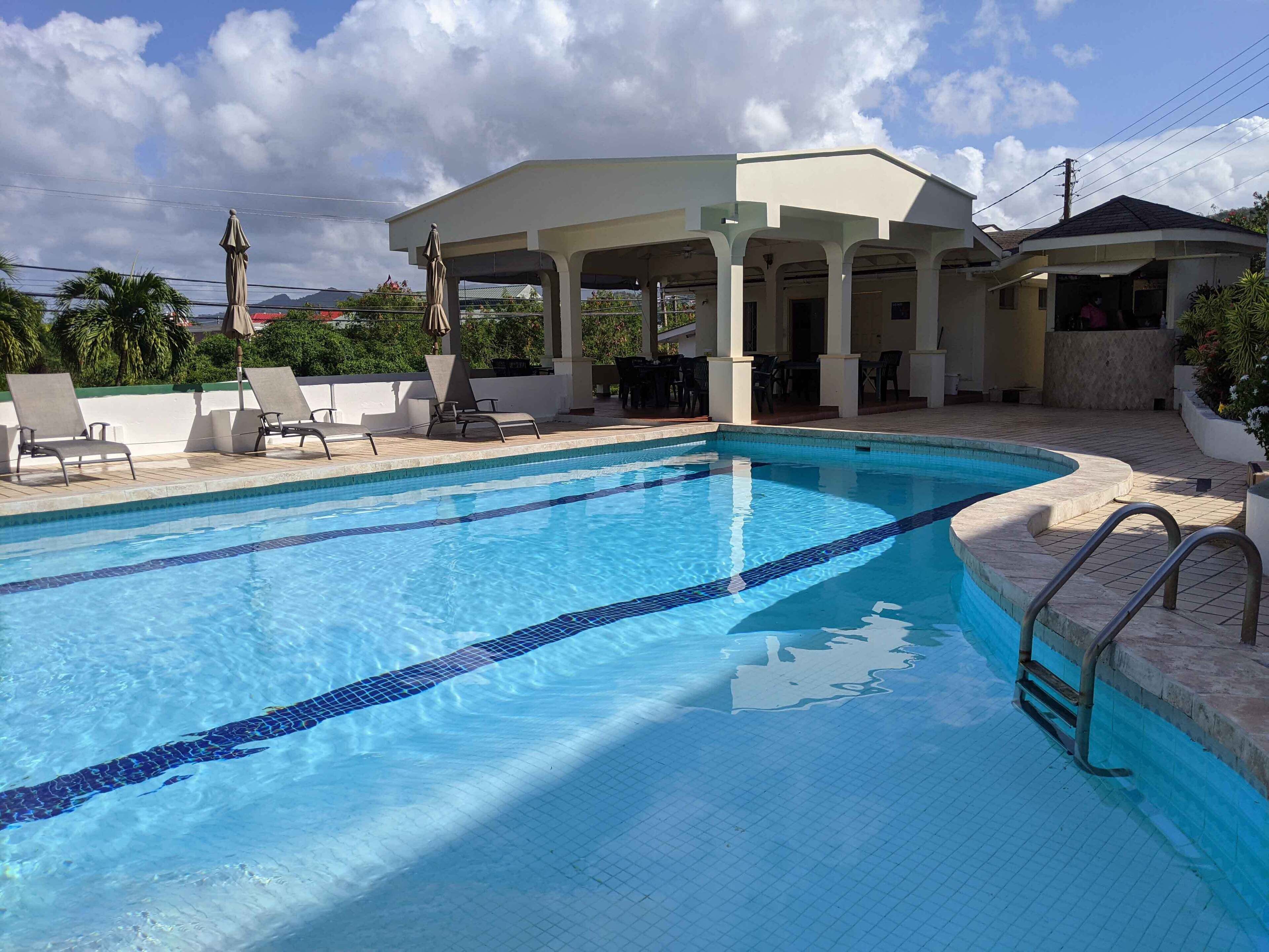 Una piscina con agua cristalina, sillas de descanso y un área de estar techada.