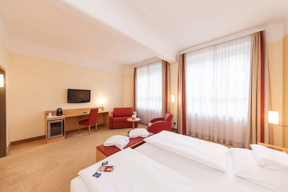 Une chambre d’hôtel avec un lit, un bureau, une chaise, une télévision et une petite table.