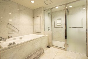 Un baño moderno con una bañera grande, una ducha con cerramiento de vidrio y un pasamanos.