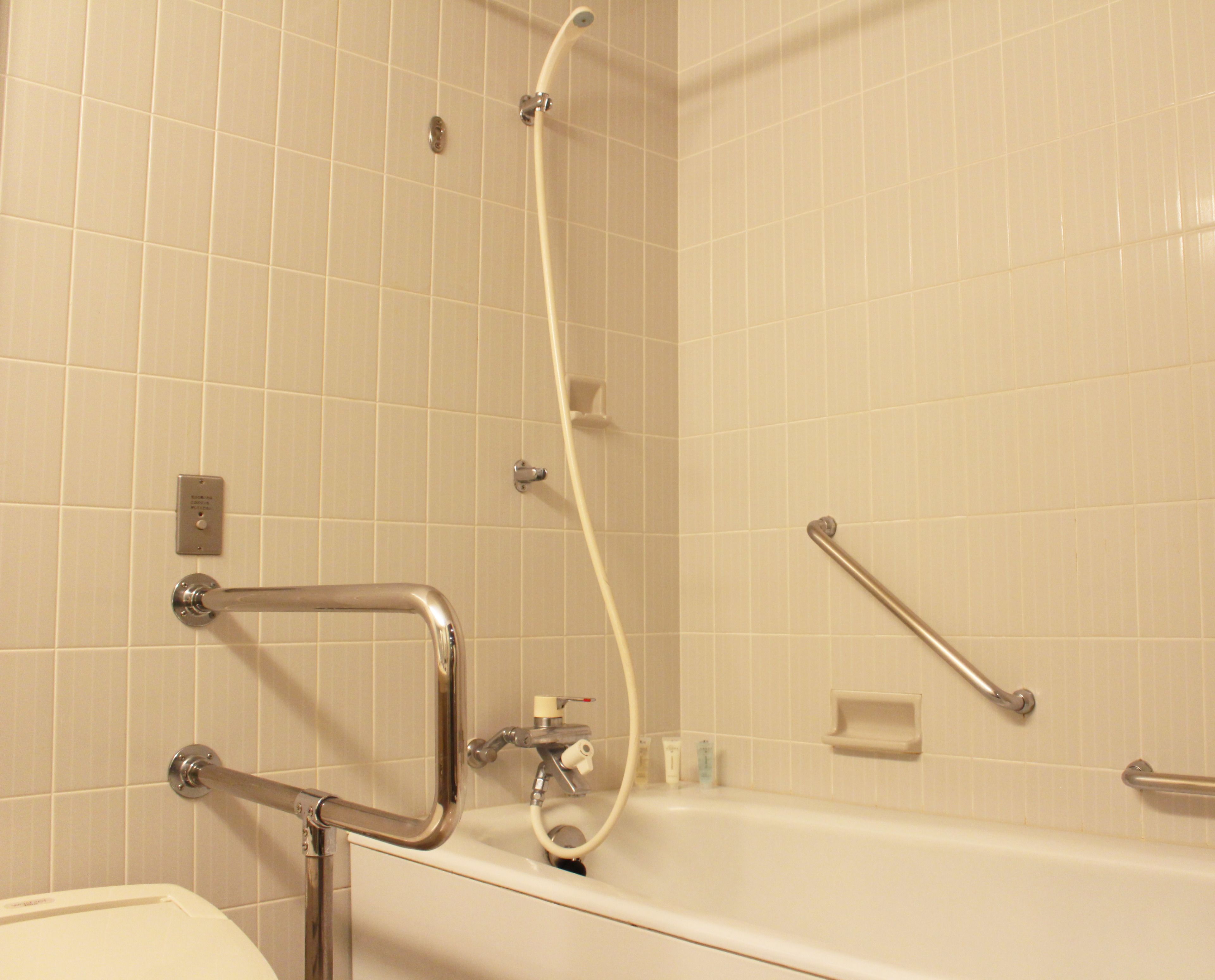 A bathroom with a bathtub, a shower, and grab bars.