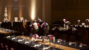 A banquet table set for a formal event with floral centerpieces, name cards, and a projection of the hotel name in the background.