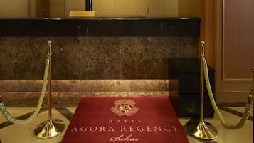 A reception area with a red carpet leading to the executive floor, a reception desk, and a reception sign.