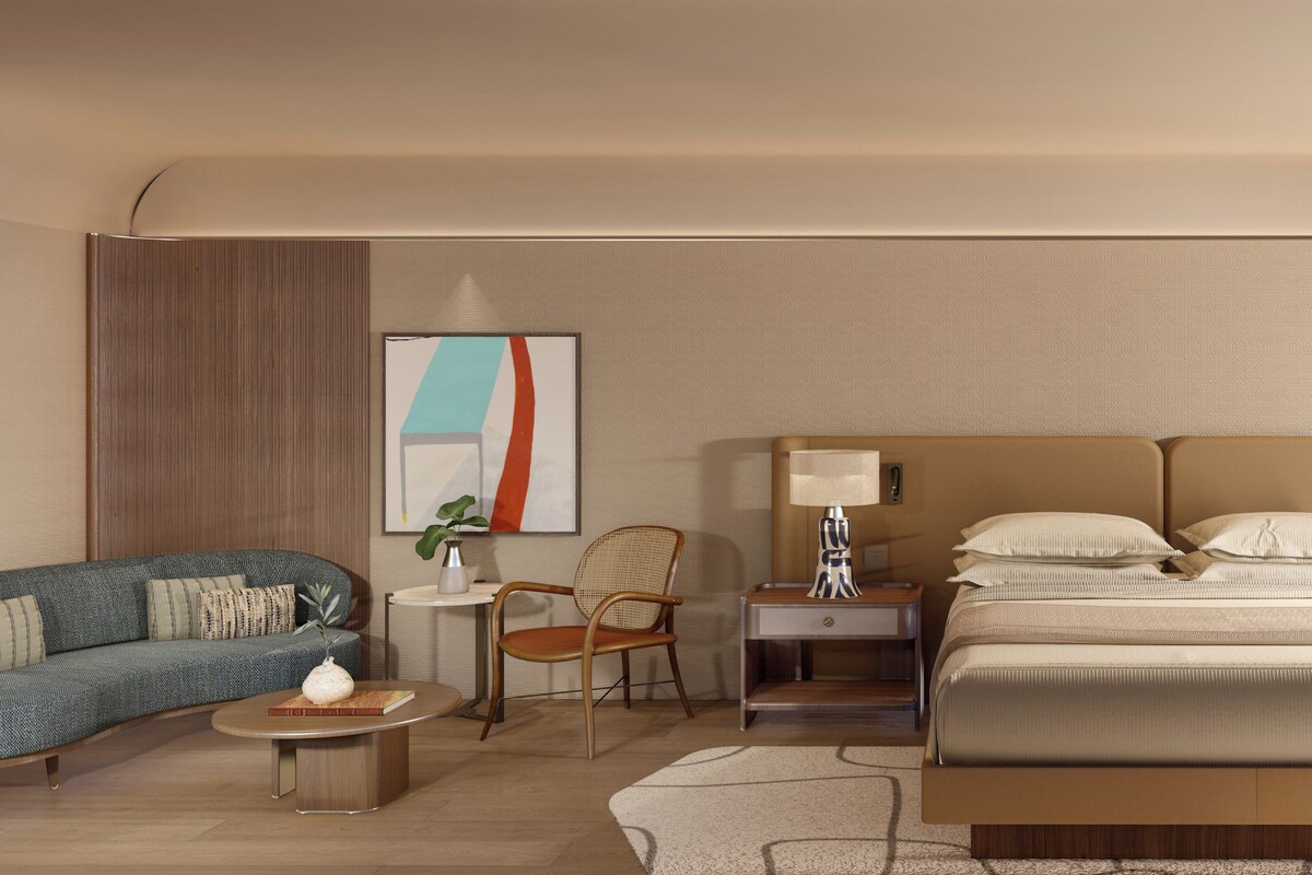 Una habitación de hotel con una cama grande, dos mesitas de noche, un sofá, una silla y una pequeña mesa con lámpara.