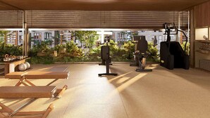 Area palestra all'aperto con attrezzature ginniche, un tavolo con kettlebell e vista sui palazzi sullo sfondo.