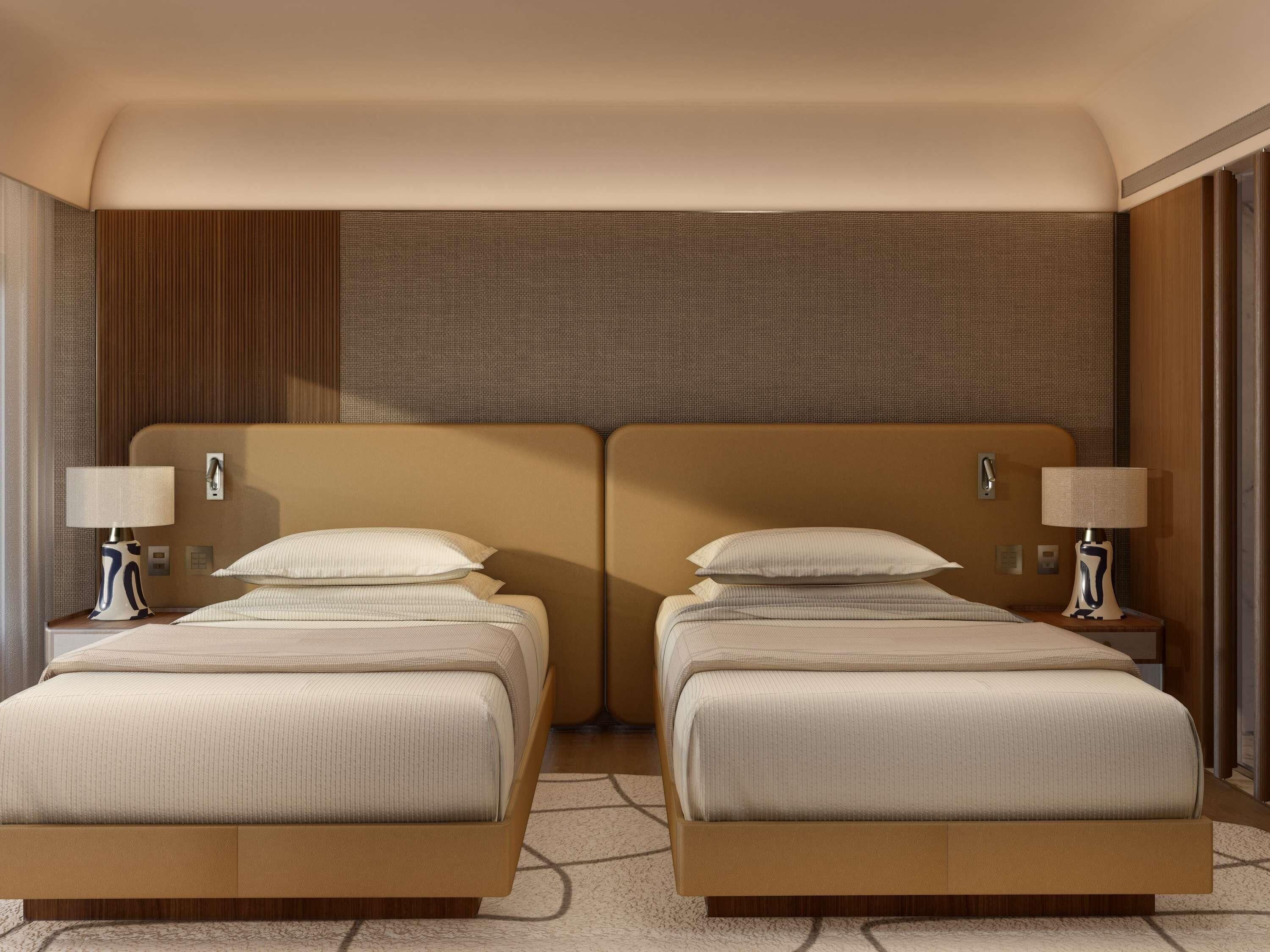 Una cama doble con cabecera, mesitas de noche con lámparas y una pared en tonos neutros.