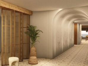 Un pasillo con una pared curva, una planta y una silla.