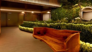 A modern interior with a wooden bench, a reception area, and a green garden.