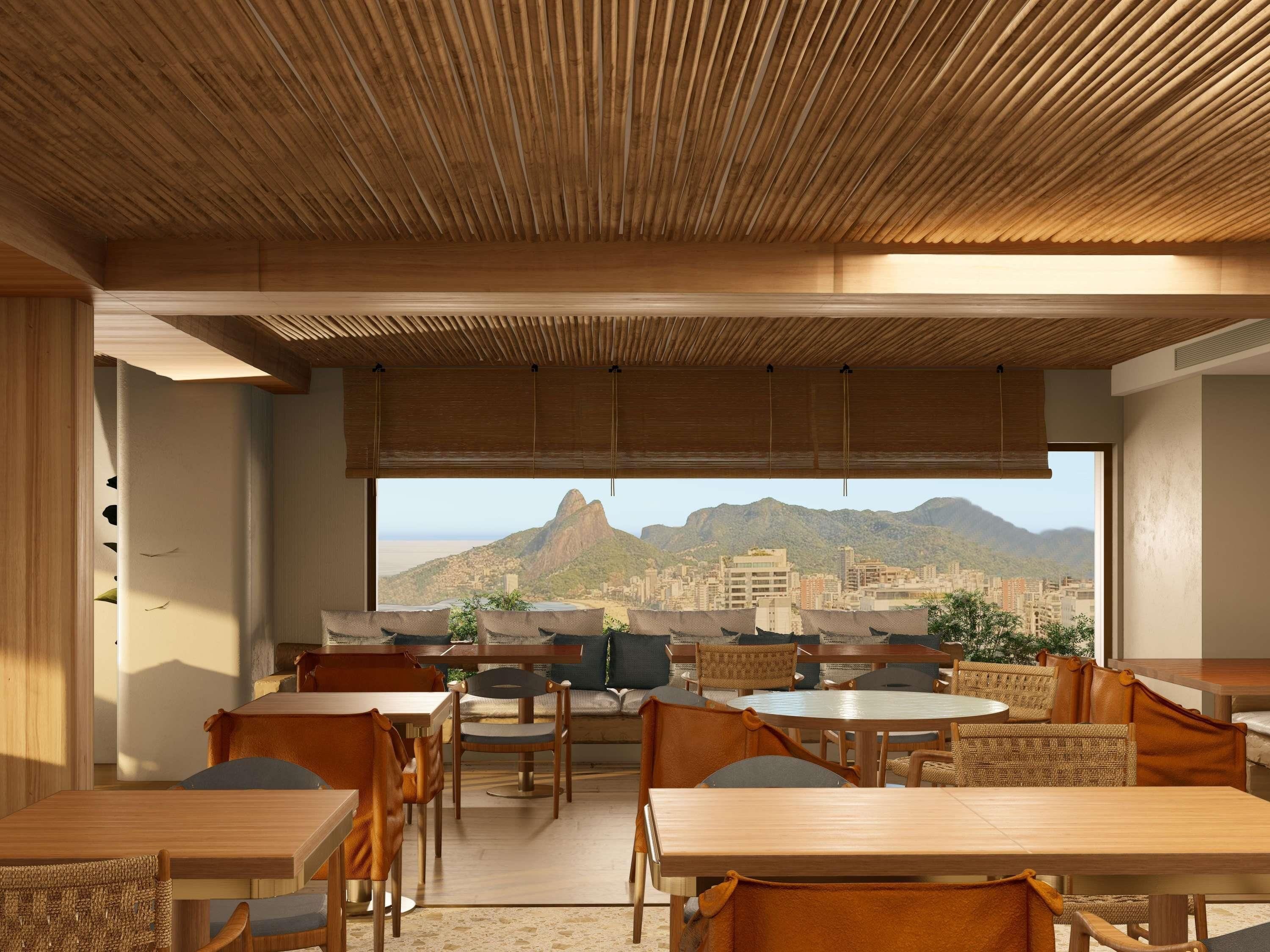 Comedor con mesas y sillas, techo de bambú y vistas a la ciudad y montañas.