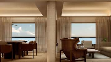 A modern living room with a large window, a dining area, and a seating arrangement.