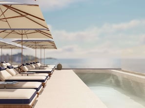 Un espace piscine aménagé sur le toit, avec des chaises longues et des parasols, offrant une vue sur une étendue d’eau.