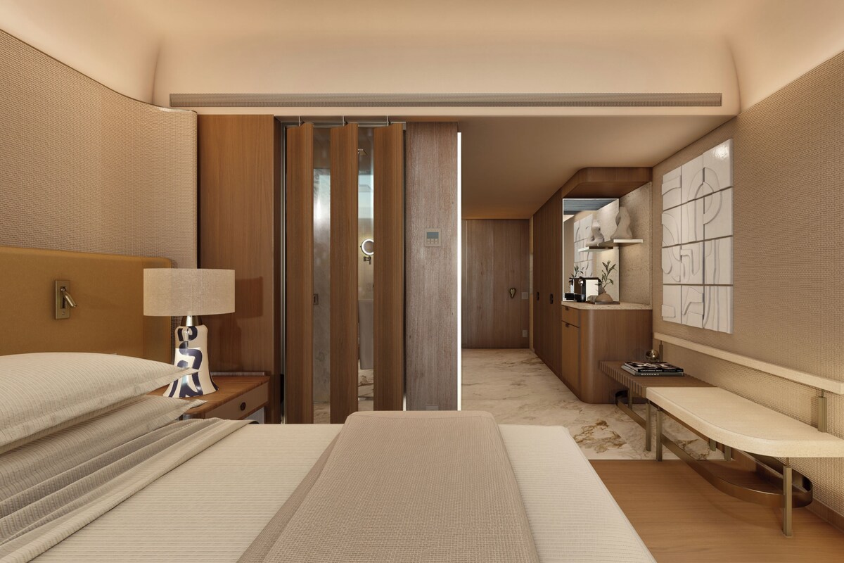 Una habitación de hotel con cama, mesita de noche, lámpara y un escritorio con silla.