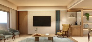 Una sala moderna con televisor de pantalla plana, dos sillones, una mesa de centro y una zona de cocina con una planta.