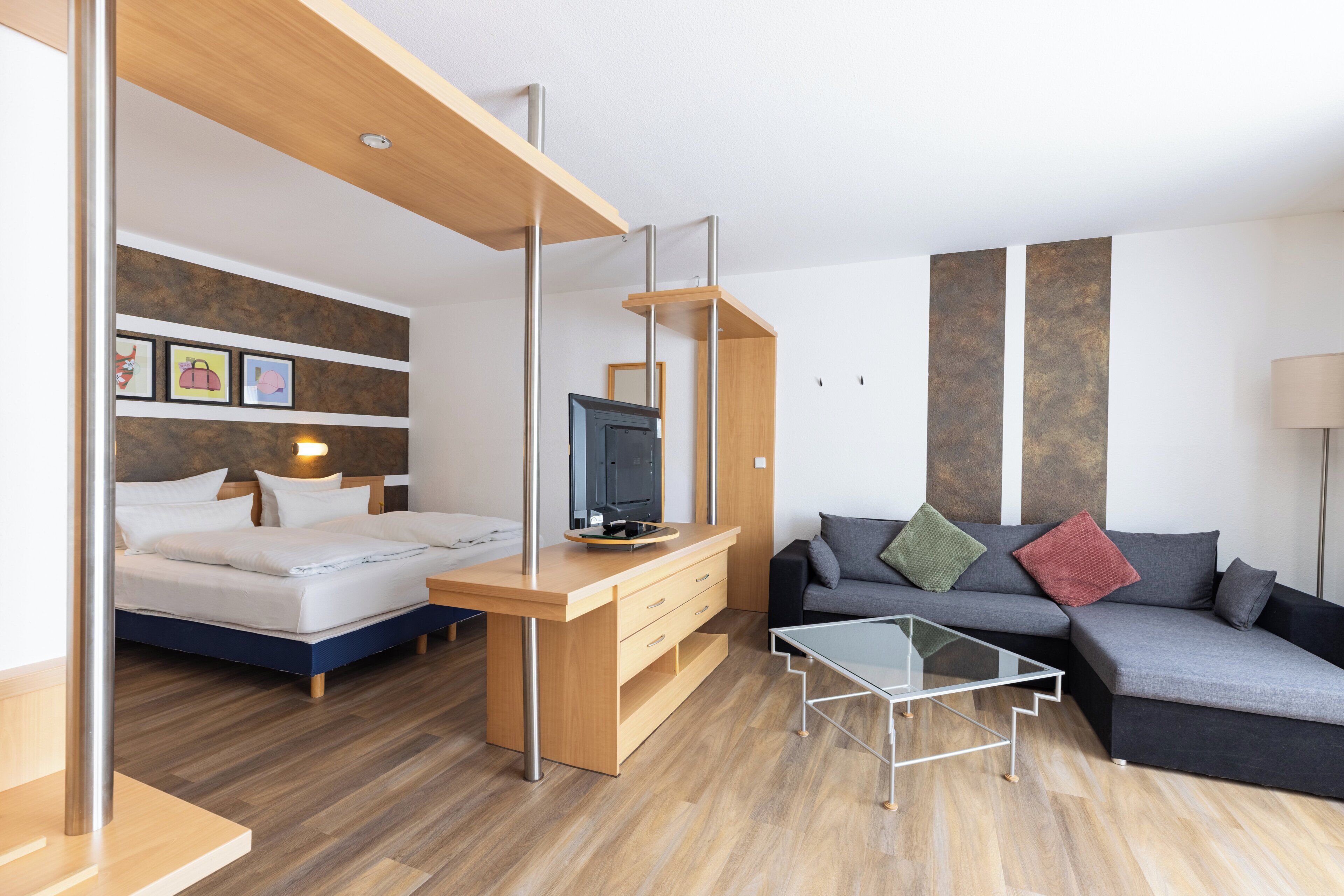 Una habitación moderna con una cama, un escritorio, un sofá y un televisor.