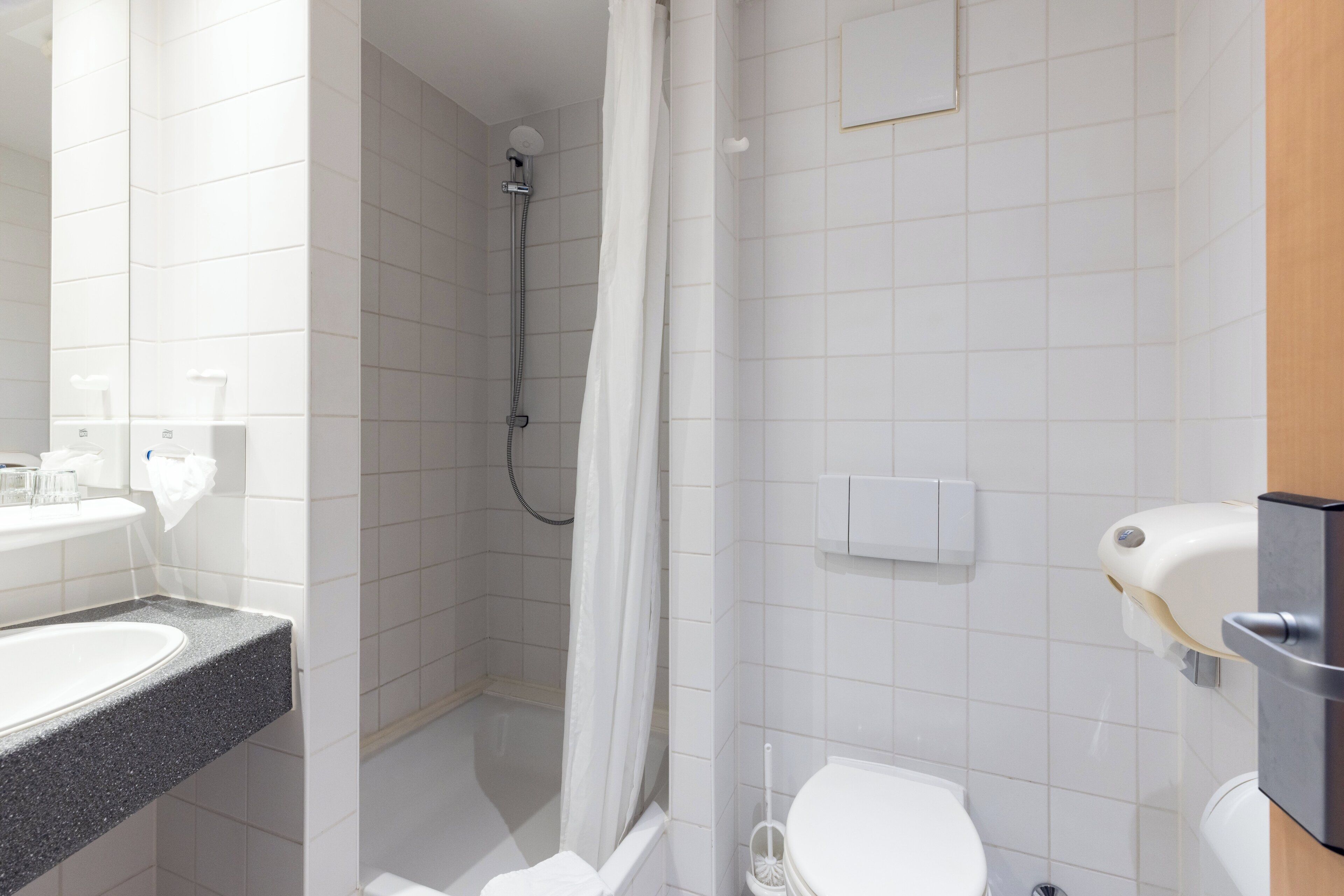 A modern bathroom with a shower, toilet, and sink.