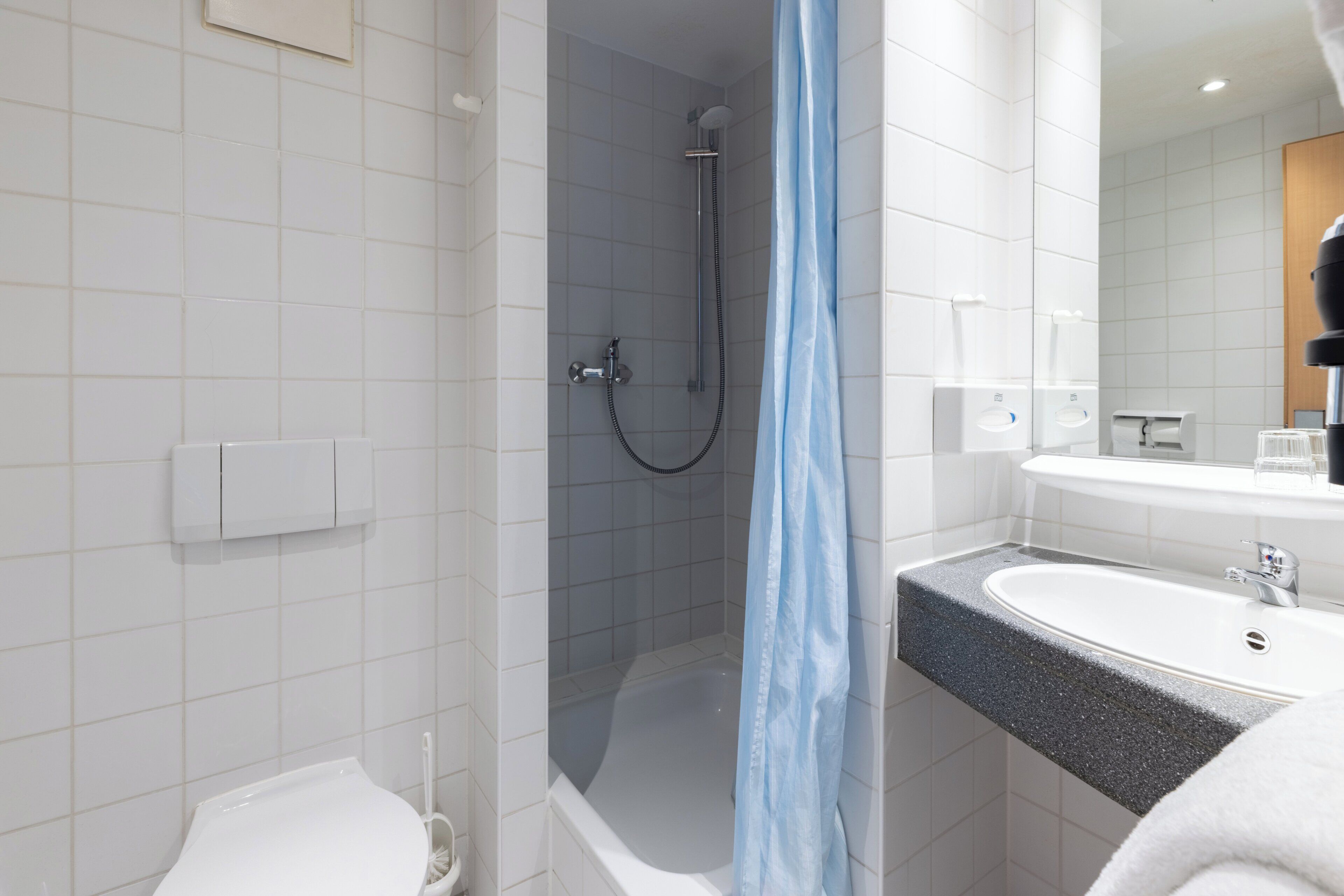 A modern bathroom with a shower, toilet, and sink.