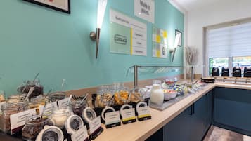 Un bufé de desayuno con diversas opciones de comida y recipientes etiquetados.
