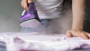 A person ironing a garment on a flat surface.