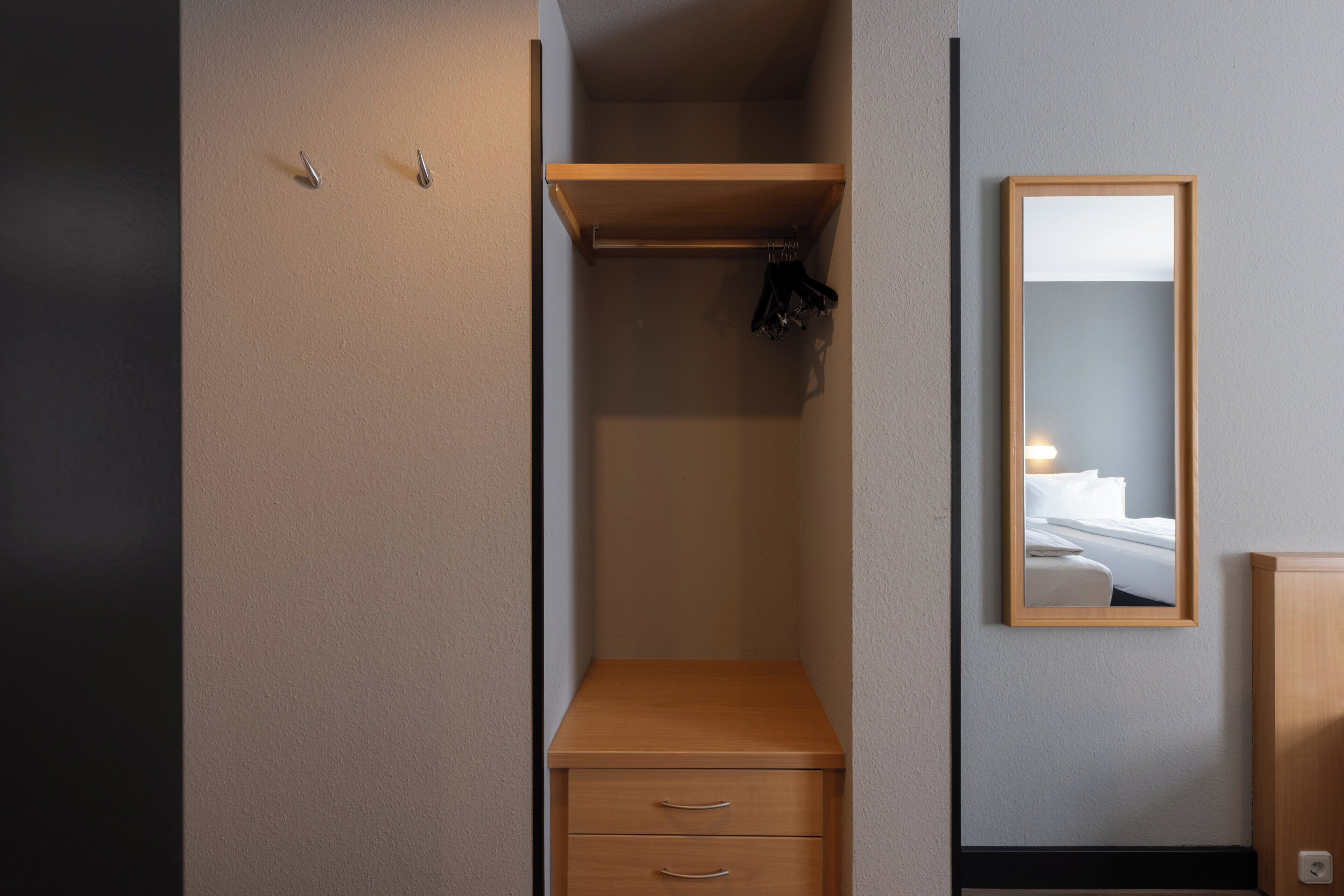 Une chambre d’hôtel avec un placard, un miroir et un lit.