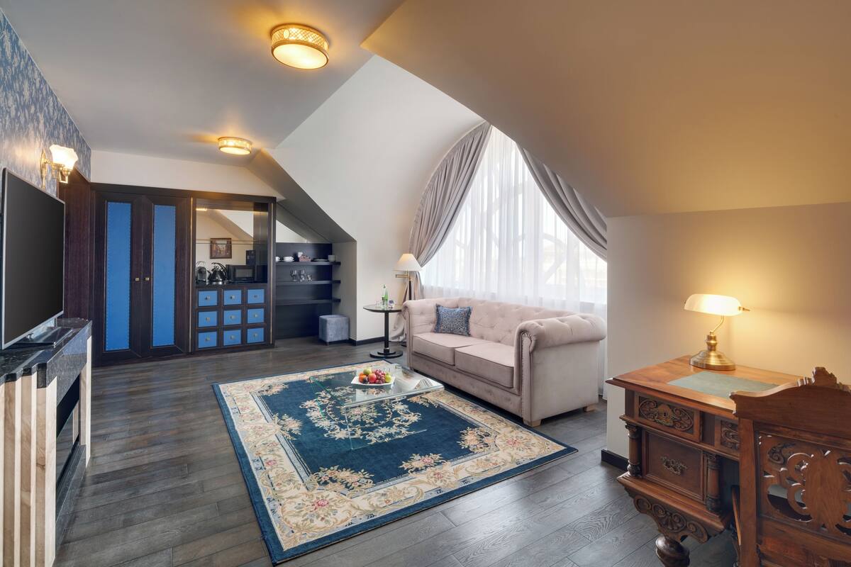 A spacious loft bedroom with a large window, a cozy seating area, and a modern kitchenette.