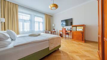 A hotel room with a large bed, a desk, a TV, and a wardrobe.