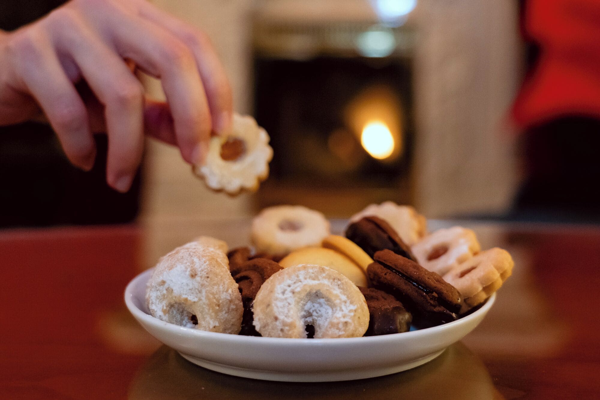 A plate of assorted pastries with a hand reaching for one.