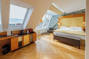 Quarto moderno com claraboia, móveis de madeira, cama com colcha amarela e vista da cidade.