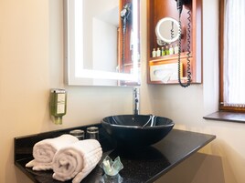 A bathroom with a black sink, a mirror, a hairdryer, and a towel rack.