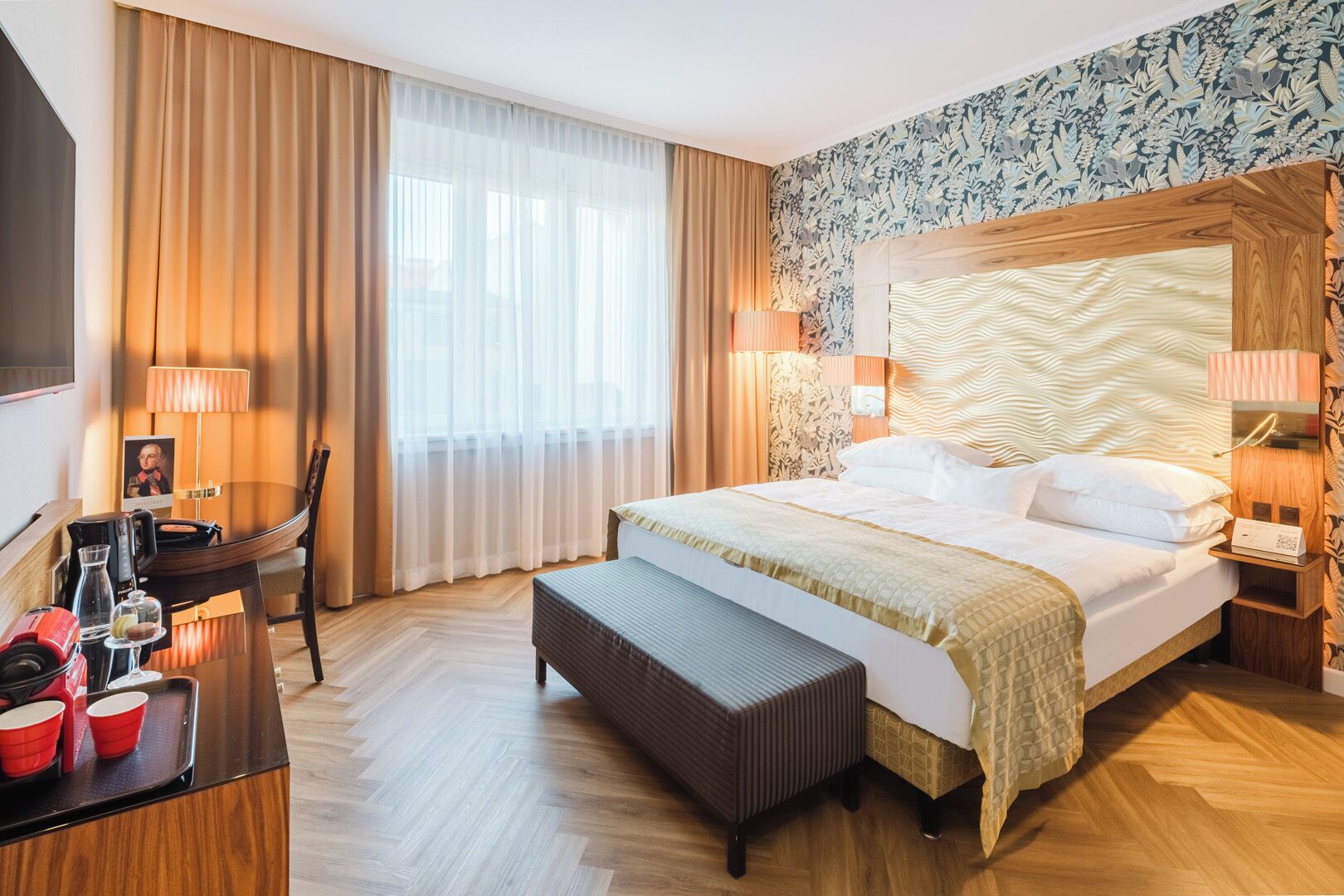 Une chambre d’hôtel avec un grand lit, un bureau avec une chaise, une télévision et un minibar.