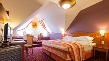 Quarto de hotel com cama, escrivaninha, cadeira e abajur.