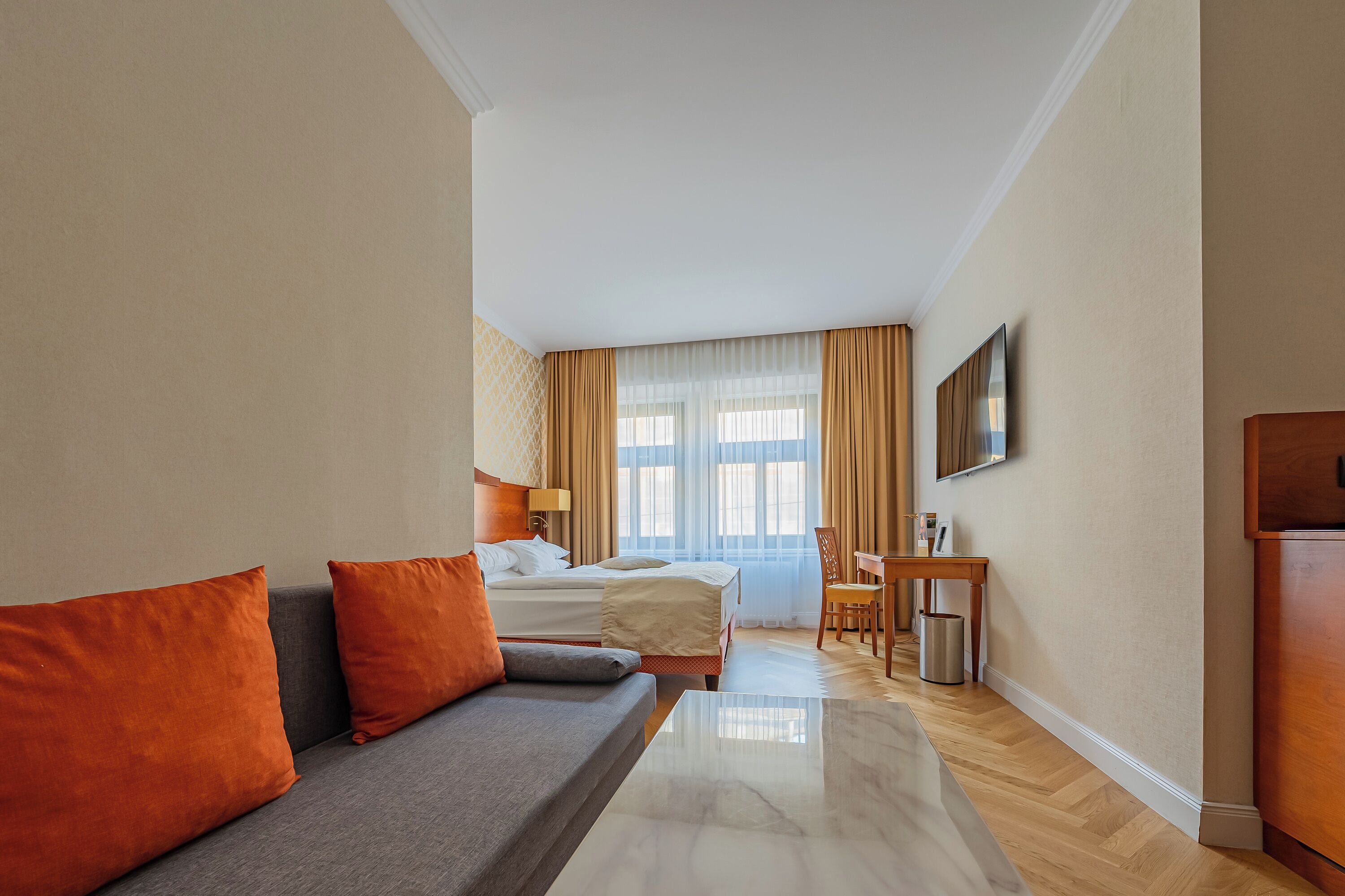 Una habitación de hotel con cama, sofá, escritorio y televisión.