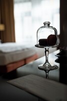 Um carrinho de sobremesas com macarons sobre uma mesa num quarto de hotel.