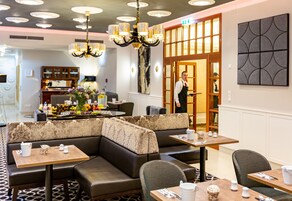 A hotel lobby with seating areas, a chandelier, and a reception desk.