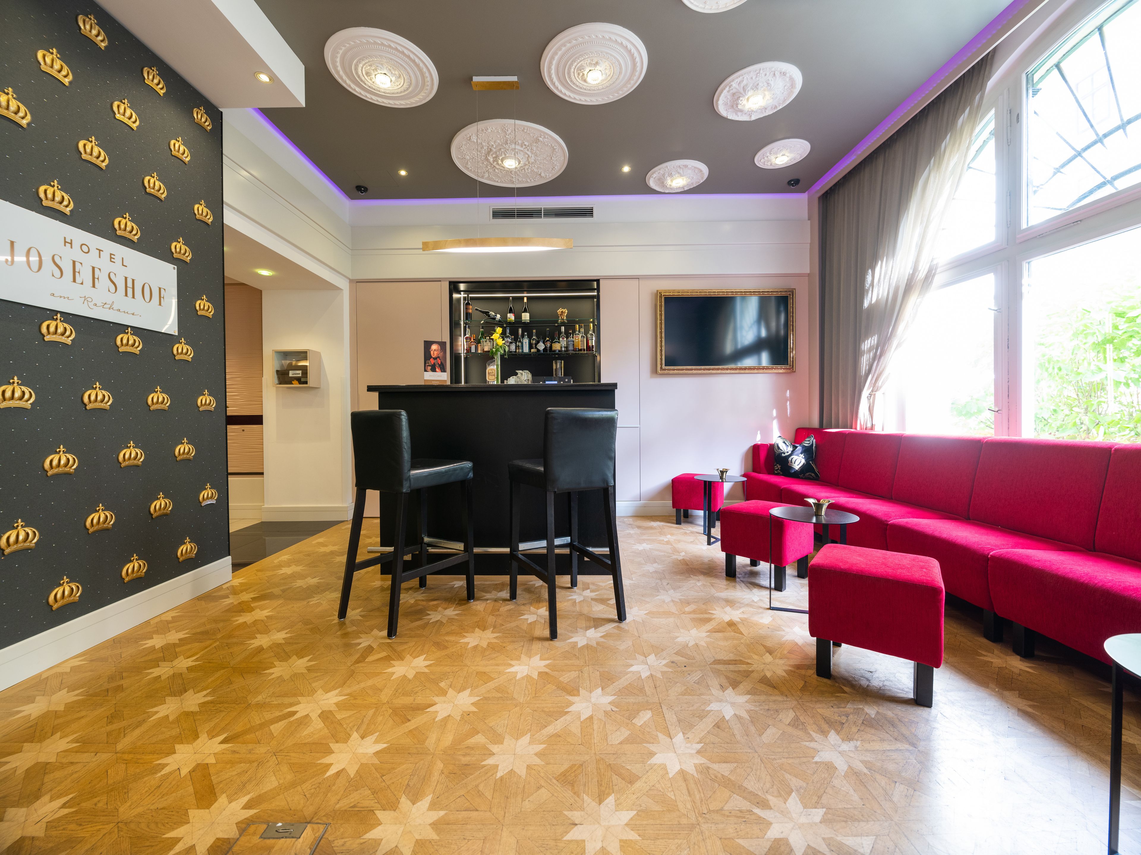 Un hall de hotel con zona de bar, un sofá rojo y un suelo estampado.