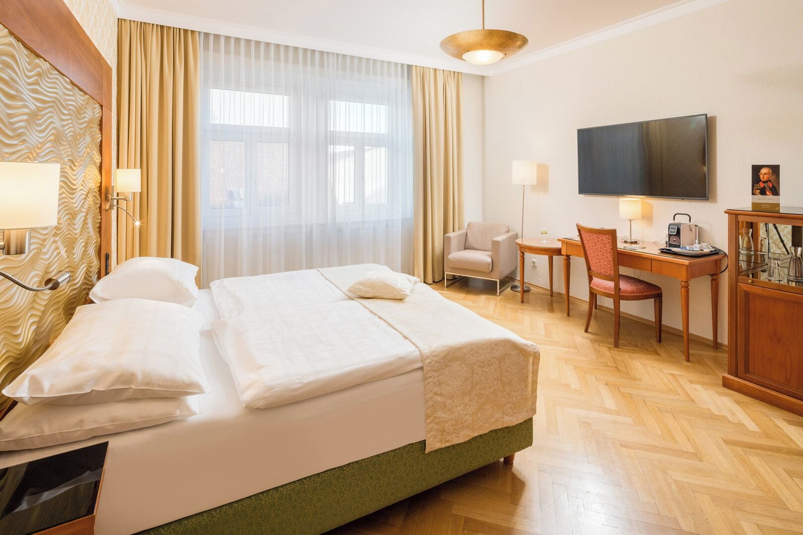 Una habitación de hotel con cama, escritorio, silla, televisión y armario.