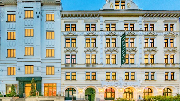 Un edificio histórico con una entrada en arco destacada, un cartel grande con el nombre 'HOTEL JOSEFSCHOF' y una escalera que conduce a la entrada.