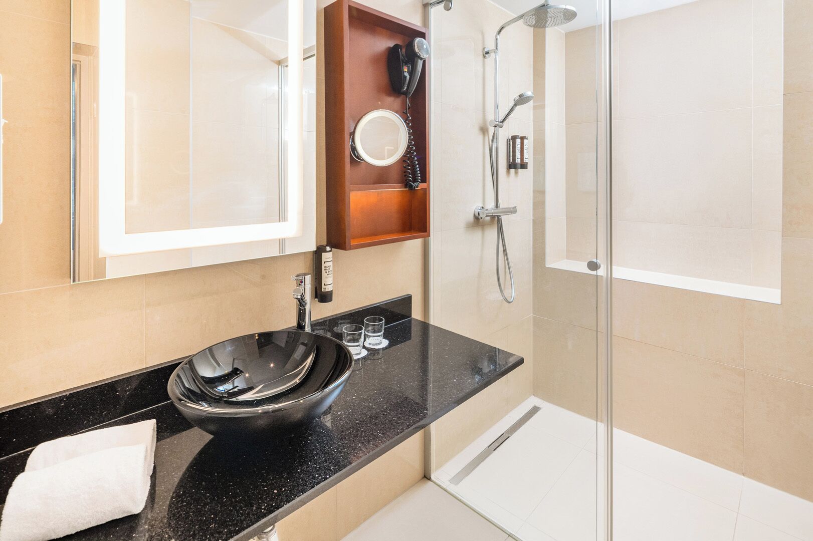 Une salle de bain moderne avec un lavabo noir, une douche en verre et un meuble-lavabo en bois.