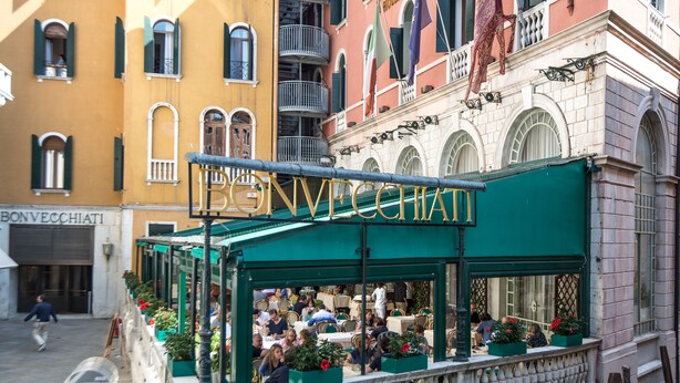 Een restaurant met terras, een groen luifel en een bord waarop staat 'Hotel Bon Vecchiati'.