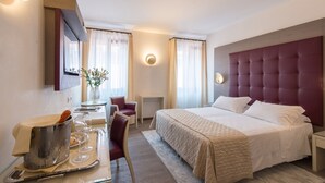 Een hotelkamer met een groot bed, een bureau met een champagne emmer en een stoel.
