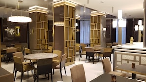 Een modern interieur met ronde tafels en stoelen, decoratieve houten panelen en sfeerverlichting.