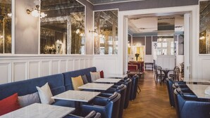 A restaurant with a long counter, blue booths, and white tables. - Henri Hotel Berlin (Berlin)
