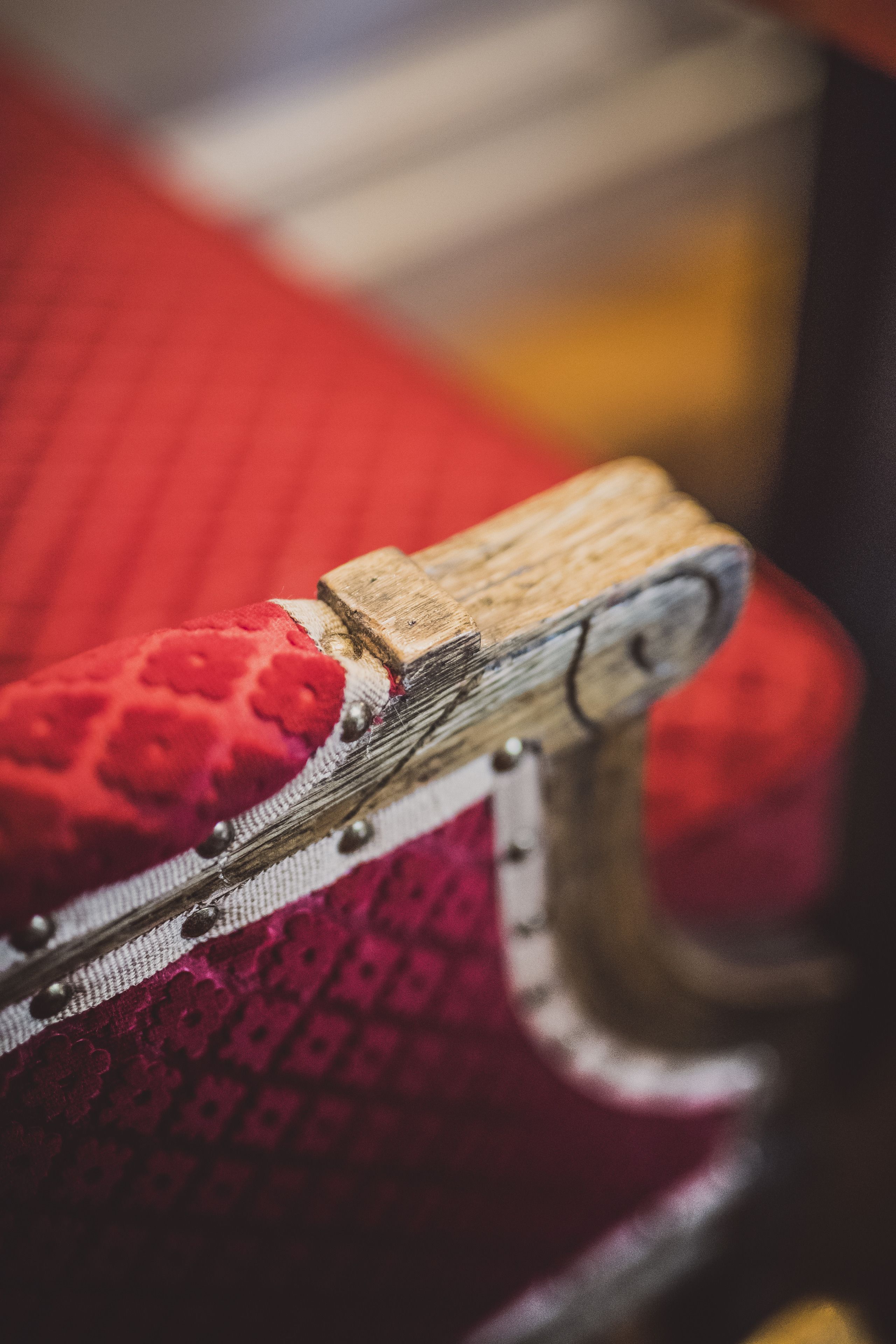 A close-up of a wooden chair with a red cushion.