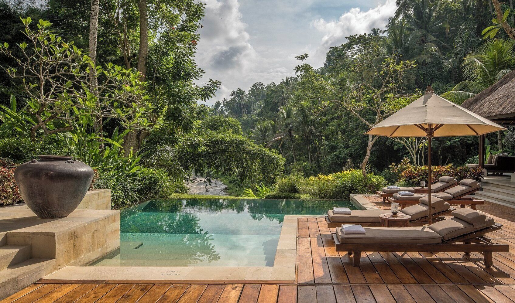 A serene outdoor pool area with lounge chairs and a large vase.