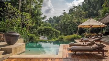 A serene outdoor pool area with lounge chairs and a large vase.