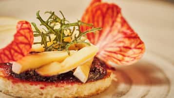A close-up of a gourmet dish with a slice of bread, cheese, and a garnish of red leaves.
