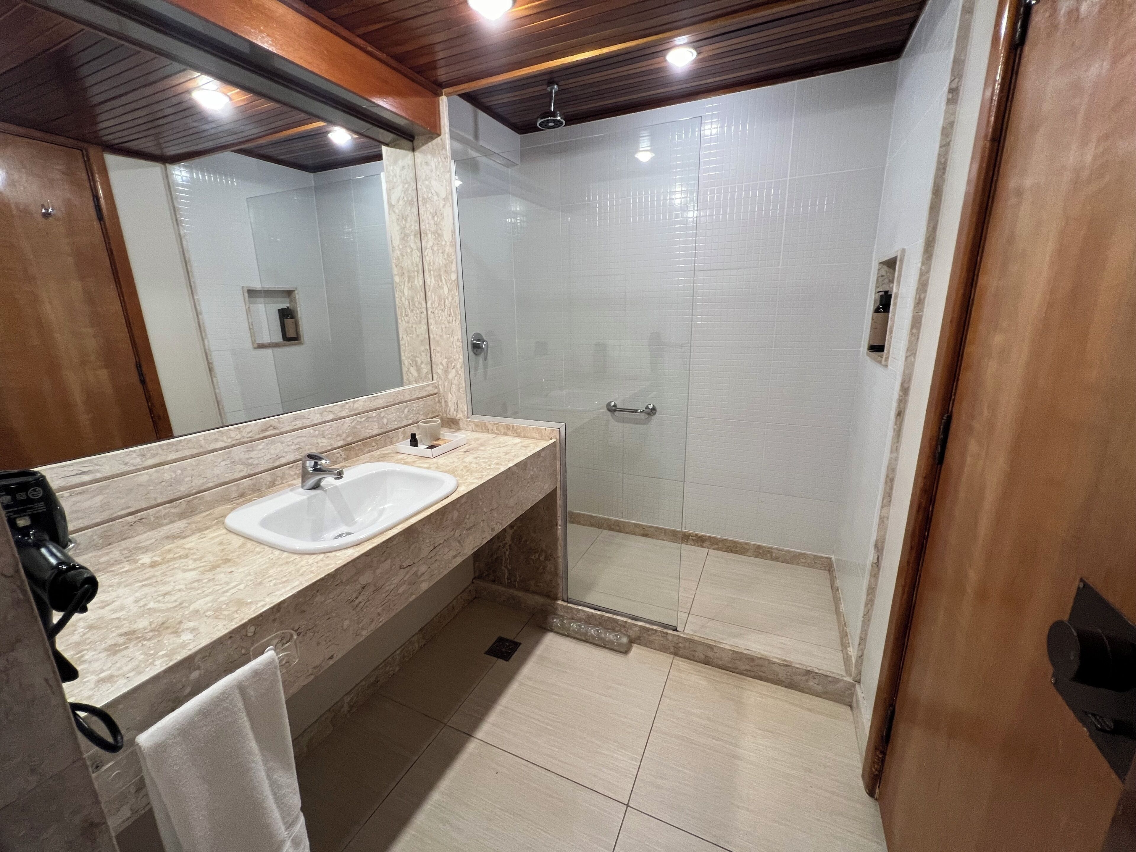 A modern bathroom with a double sink, a glass shower enclosure, and a large mirror.